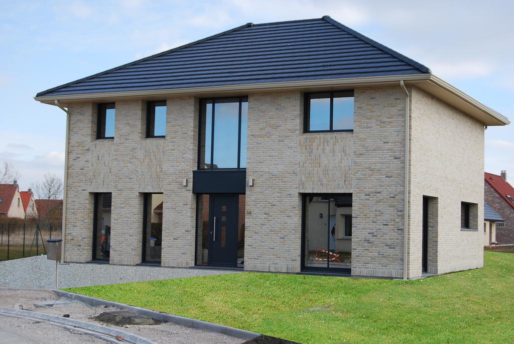 Maison individuelle grandement vitrée avec un grand espace vert non arboré