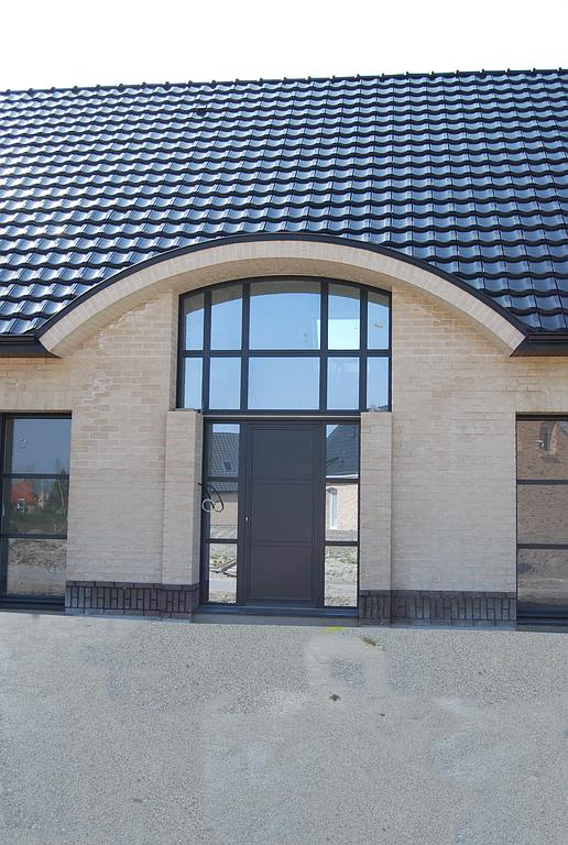 Porte d'entrée sur mesure d'une maison neuve. La porte est noirée avec du vitrage l'entourant entièrement