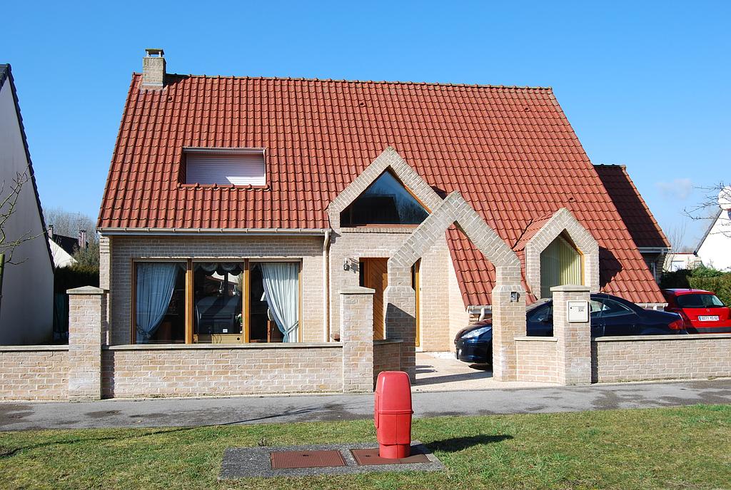 Maison individuelle de plain-pied avec muret en pierre de même couleur que la maison