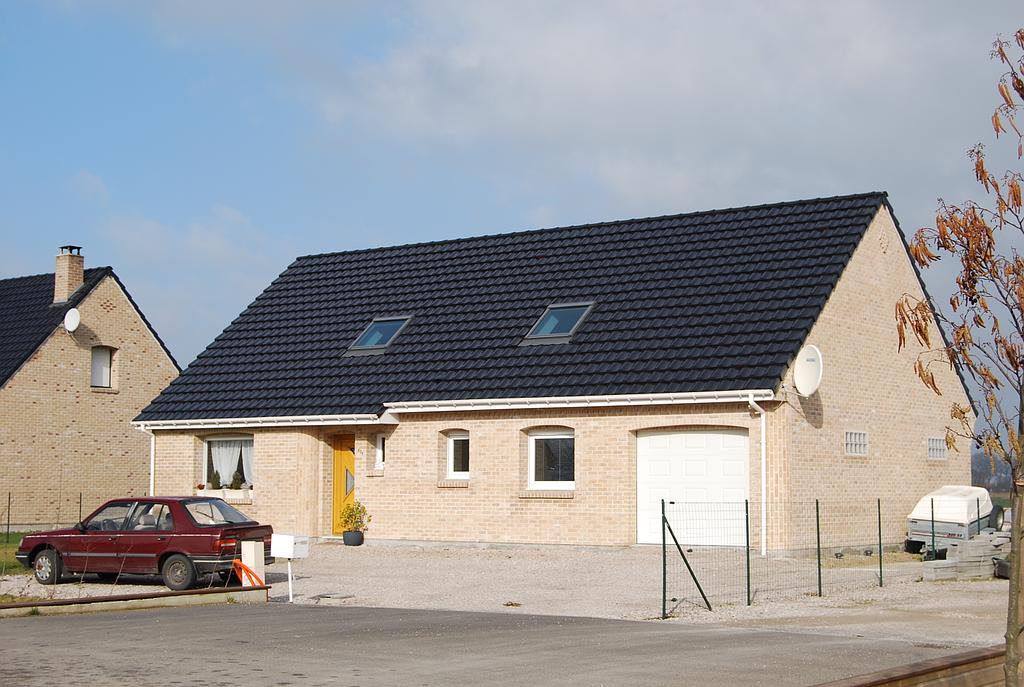 Maison individuelle sur un terrain privé délimité par un grillage et avec une porte en bois brut semi-vitrée