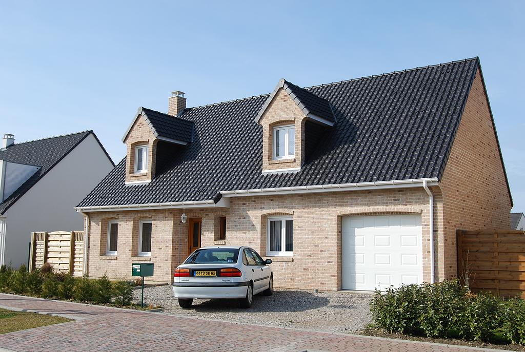 Maison individuelle avec toit en tuiles noires et menuiseries en PVC située dans un quartier d'habitation