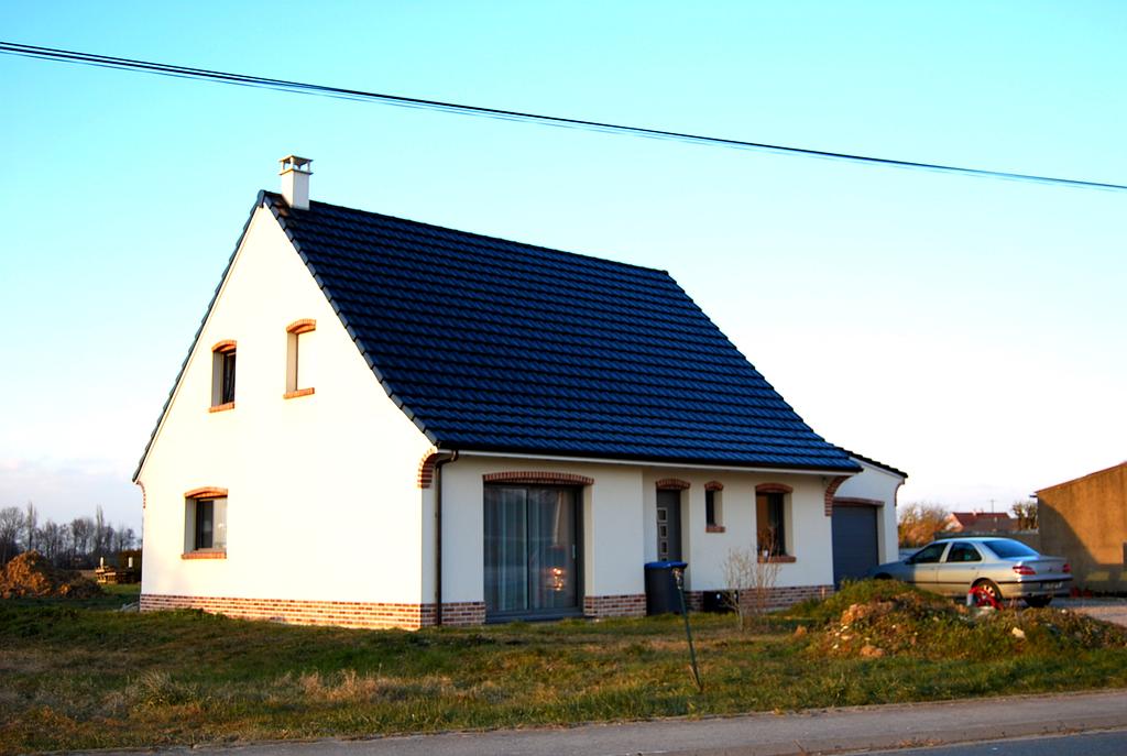 Maison d'habitation neuve blanche et dont les contours et ceux des menuiseries sont en briques aux tons de rouge