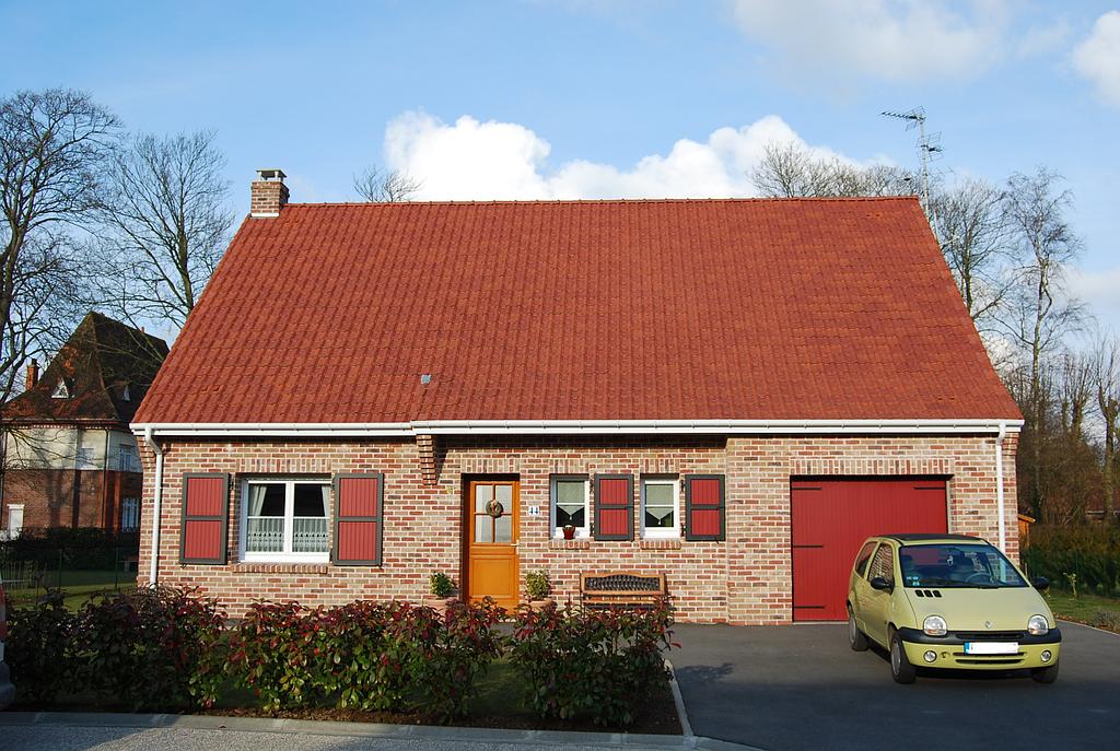 Maison individuelle en briques rouges avec menuiseries extérieures noires et rouges