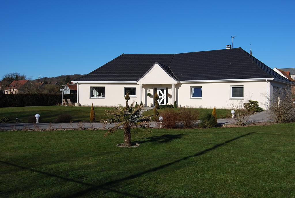 Maison à la façade blanche en angle, avec grand espace vert arboré