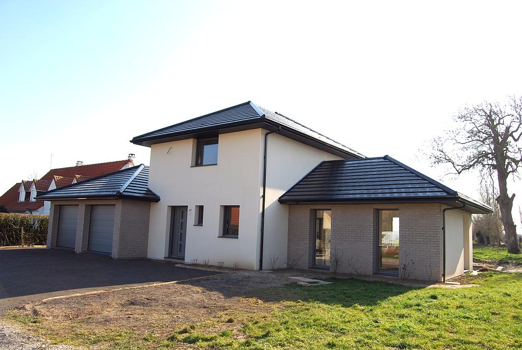 Maison individuelle dont le centre est en crépis blanc tandis que les garages et la pièce à vivre sont en briques au ton foncé