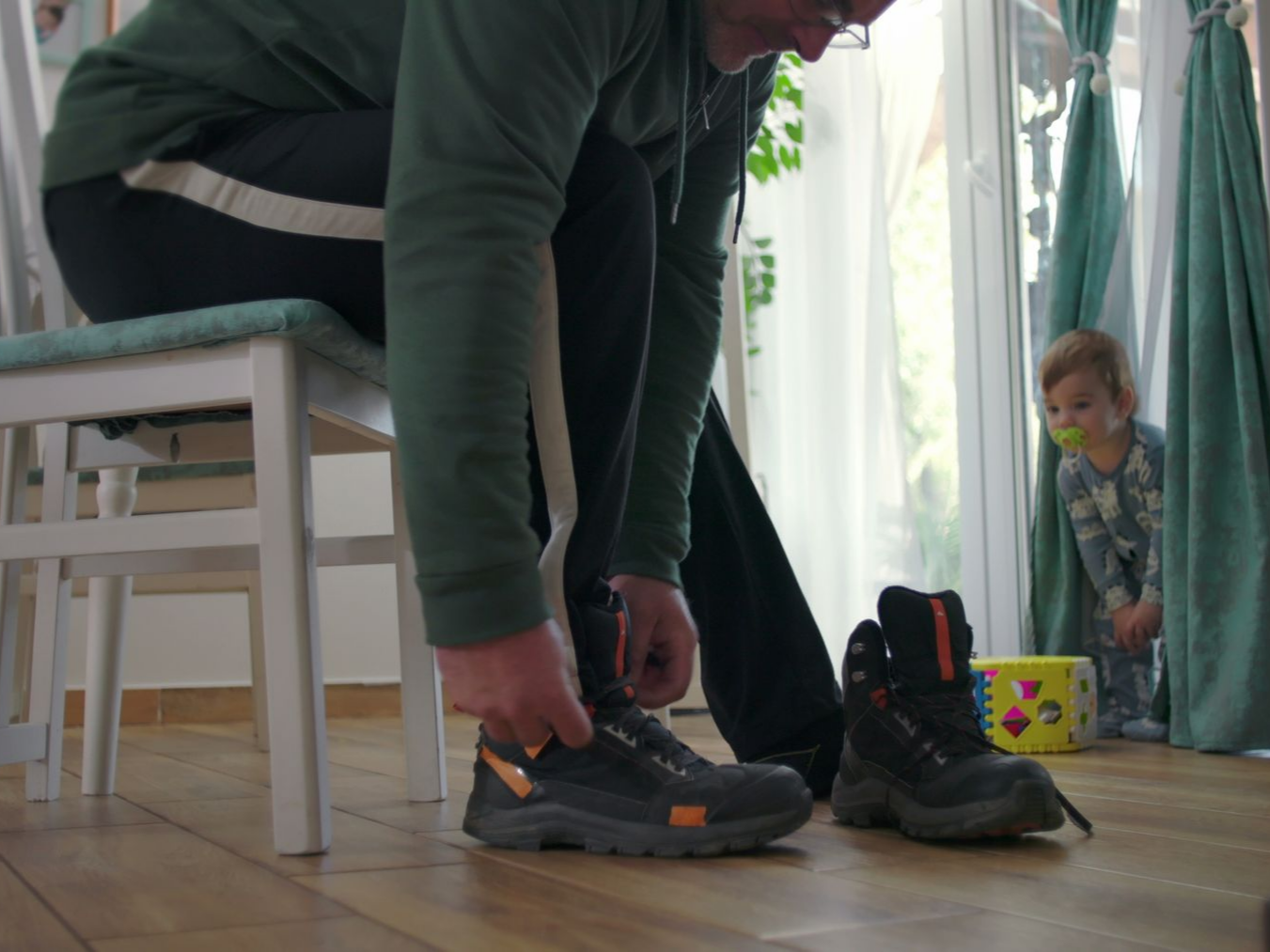 Un père fait ses lacets avec son fils à côté