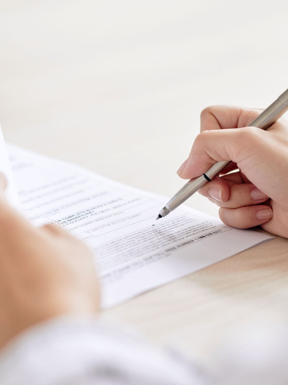 Main d'une personne écrivant sur un papier avec un stylo 