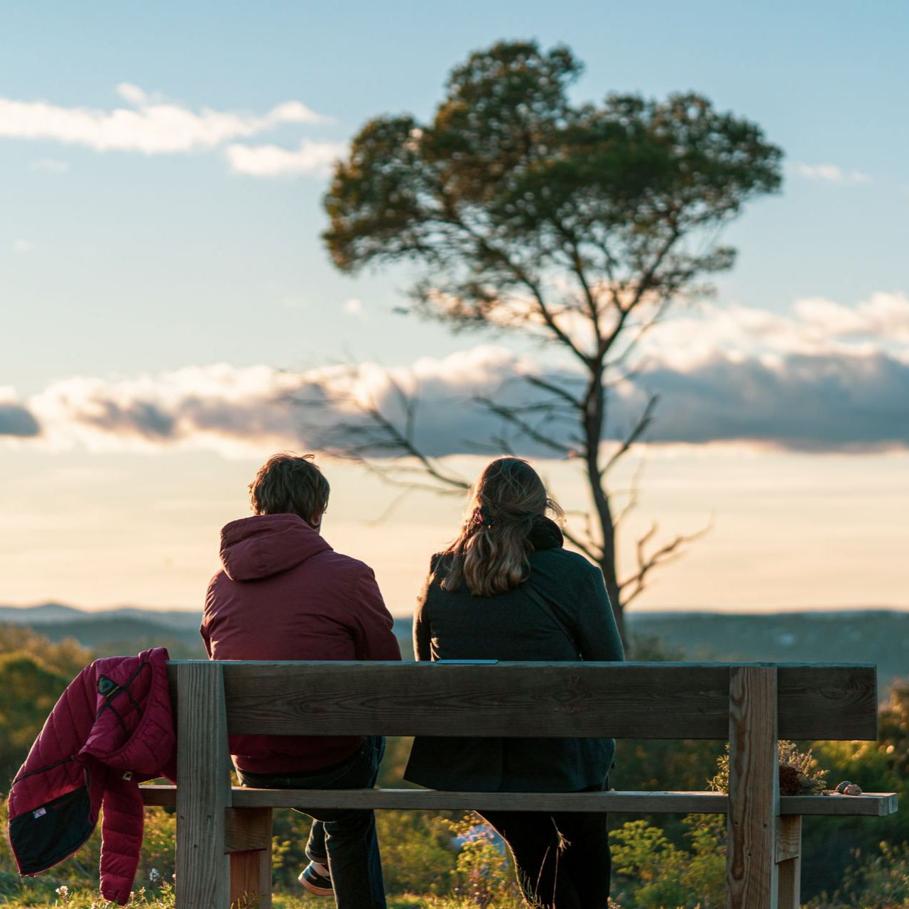Deux personnes assises sur un banc, surplombant un paysage pittoresque 