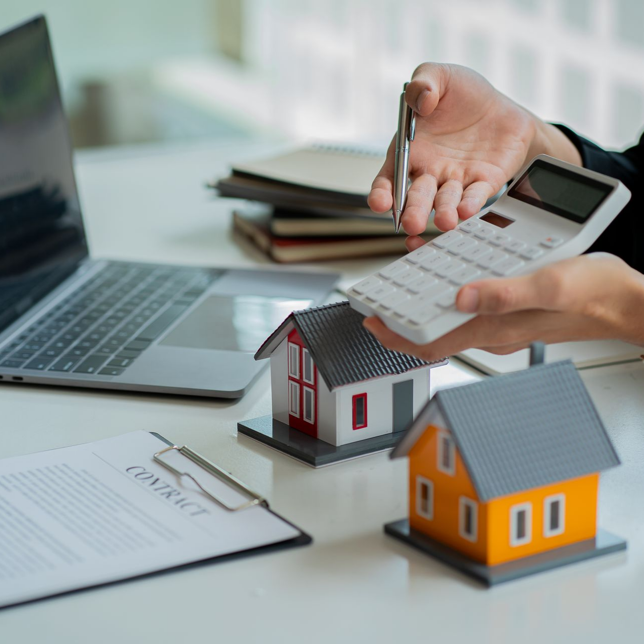 Personne utilisant une calculatrice à proximité de maisons modèles