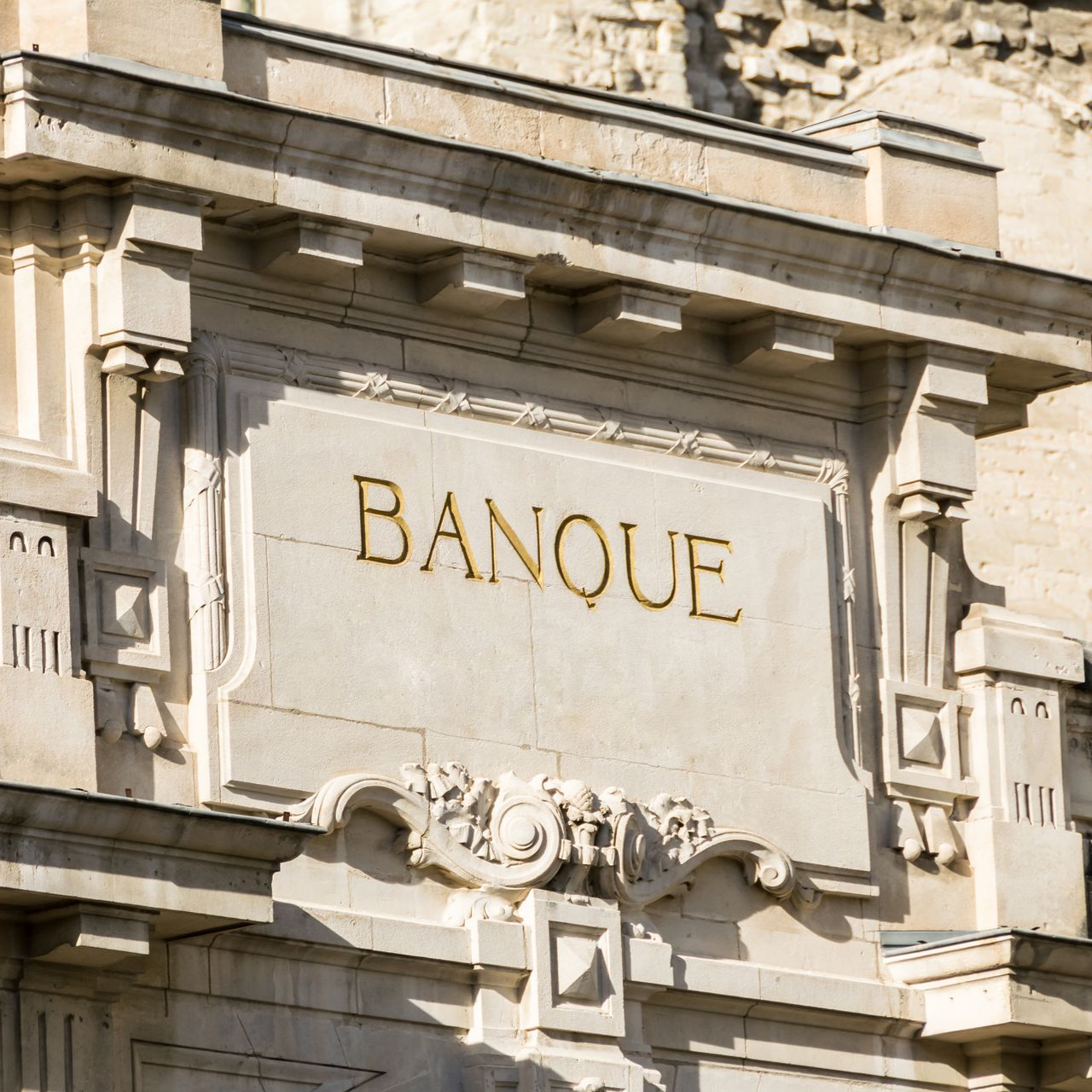 Enseigne « Banque » en lettres dorées sur une façade d'immeuble 
