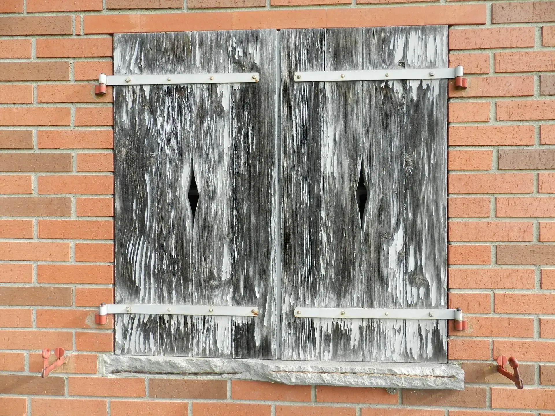 eine Backsteinmauer mit einem Fenster mit Fensterläden