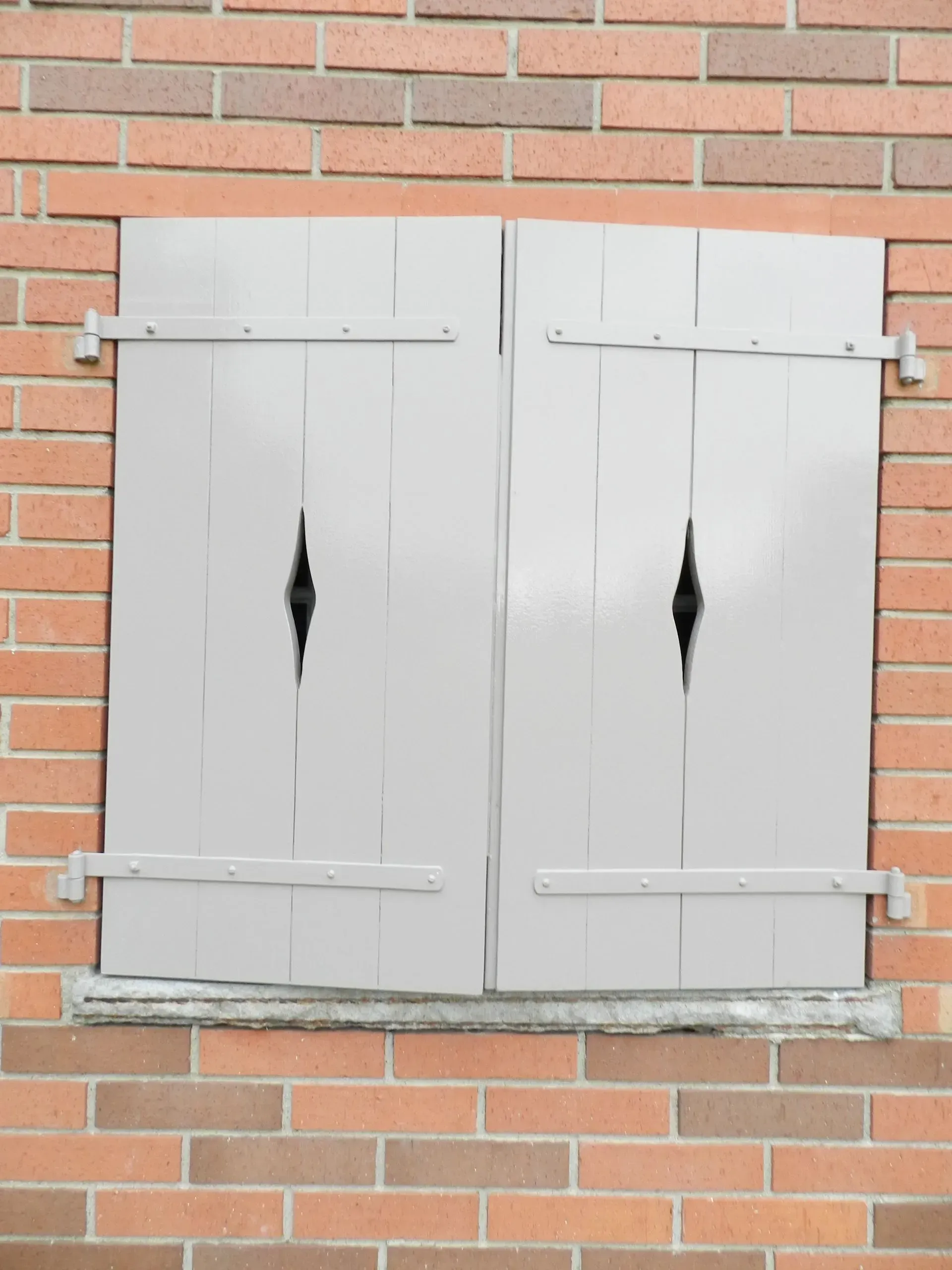 eine Backsteinmauer mit einem Fenster mit Fensterläden