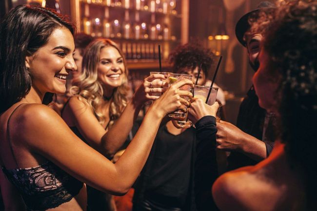 Un grupo de personas está brindando con bebidas en un bar.