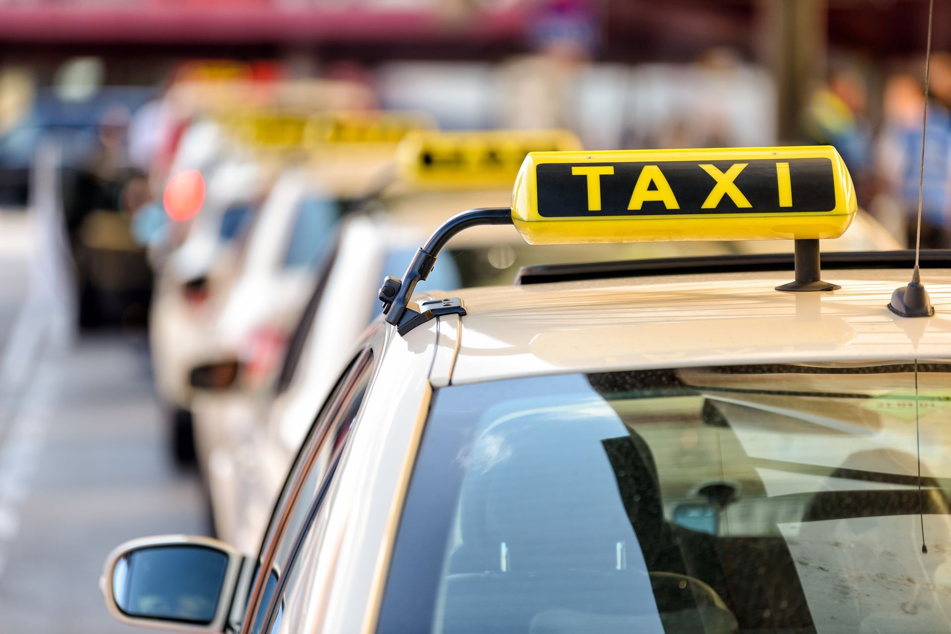 Une rangée de taxis blancs avec des gyrophares jaunes garés le long d'une rue.
