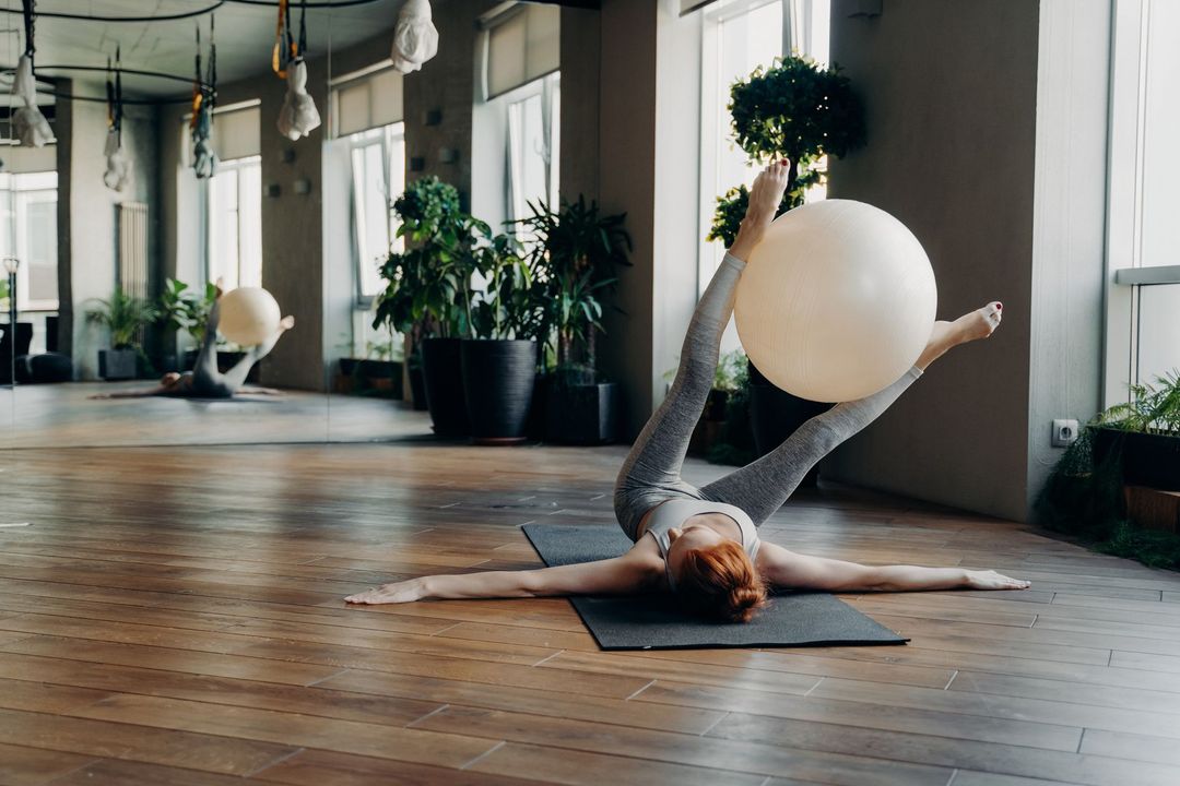 Dos mujeres están haciendo ejercicios en colchonetas de yoga en un gimnasio.