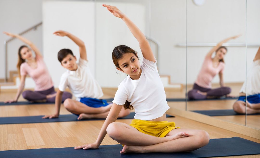 Dos mujeres están haciendo ejercicios en colchonetas de yoga en un gimnasio.