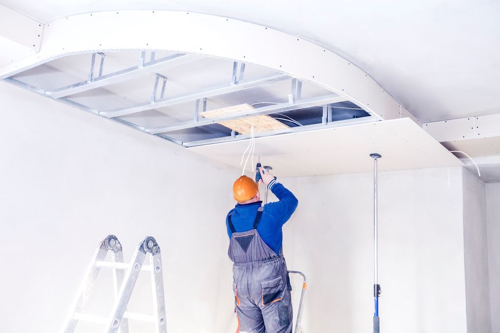 Ouvrier posant des dalles décoratives au plafond