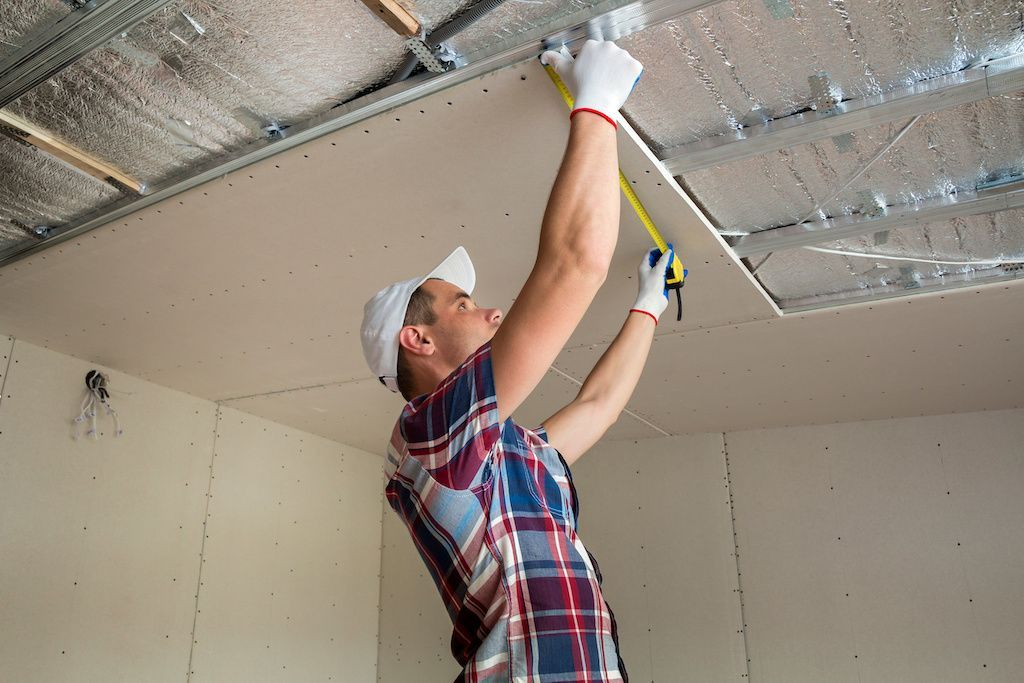 Ouvrier prenant des mesures pour l'isolation du plafond