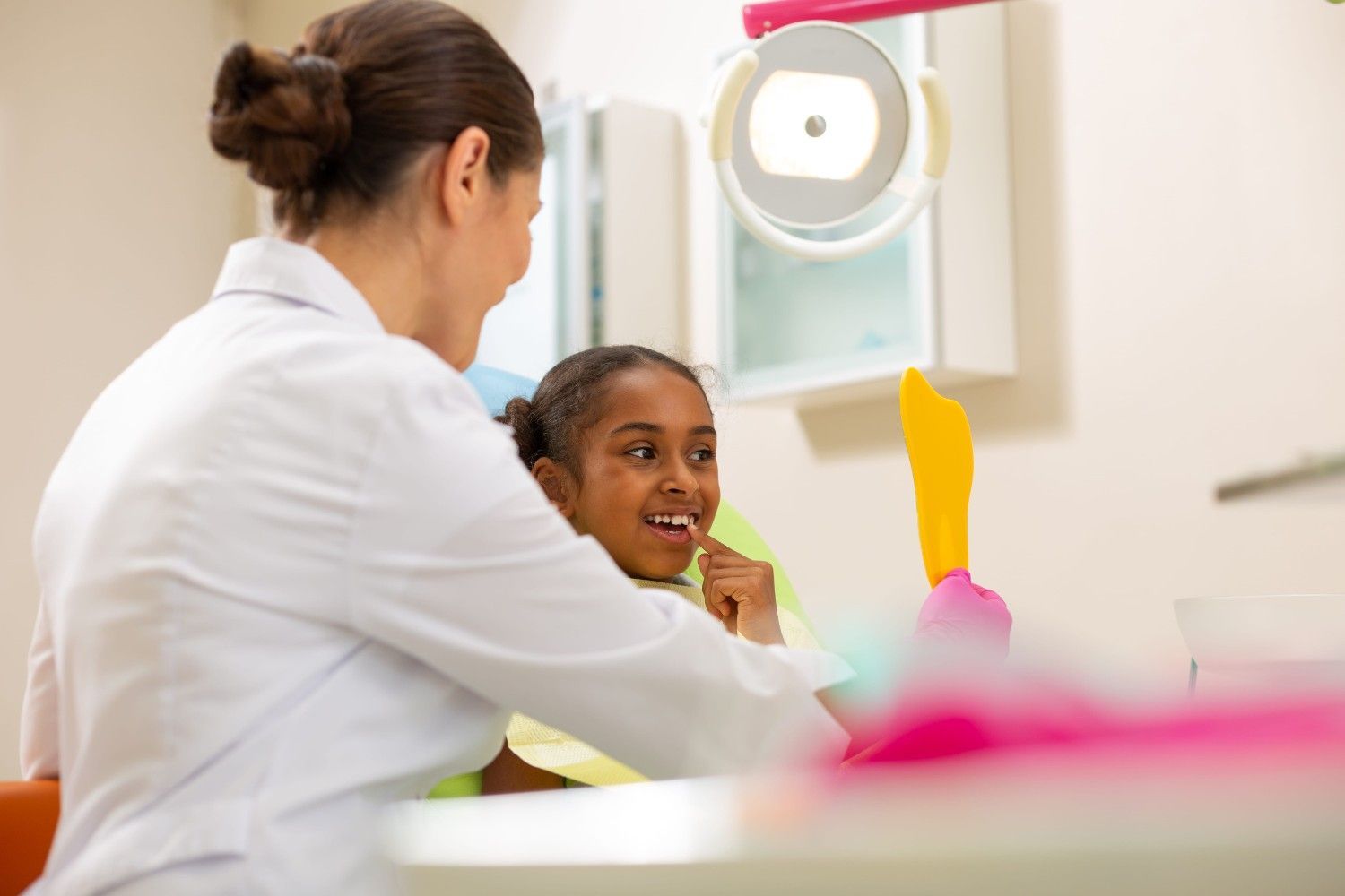 Un dentista examina a un niño sonriente en una clínica luminosa, con un modelo de cepillo de dientes en primer plano.