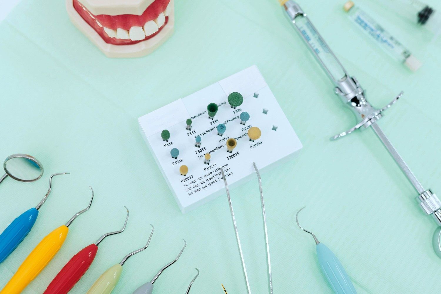 Instrumentos dentales y ficha dental sobre una superficie de clínica dental de color verde menta.