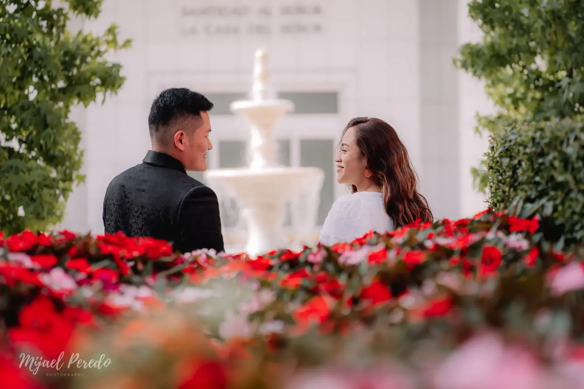 Dos personas sentadas una frente a la otra en un jardín de flores