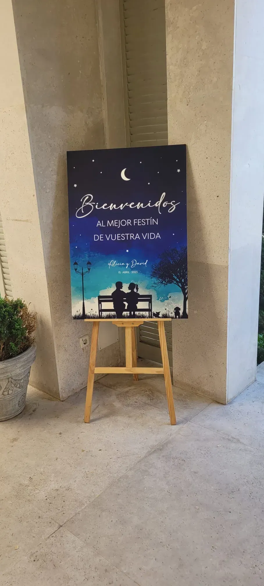 Cartel del evento sobre un caballete en un pasillo de color beige