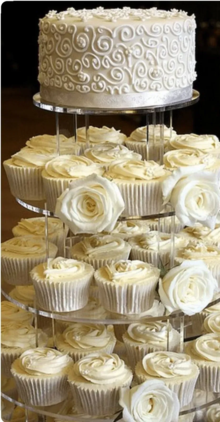 Elegante expositor de cupcakes blancos de varios niveles con cupcakes glaseados blancos