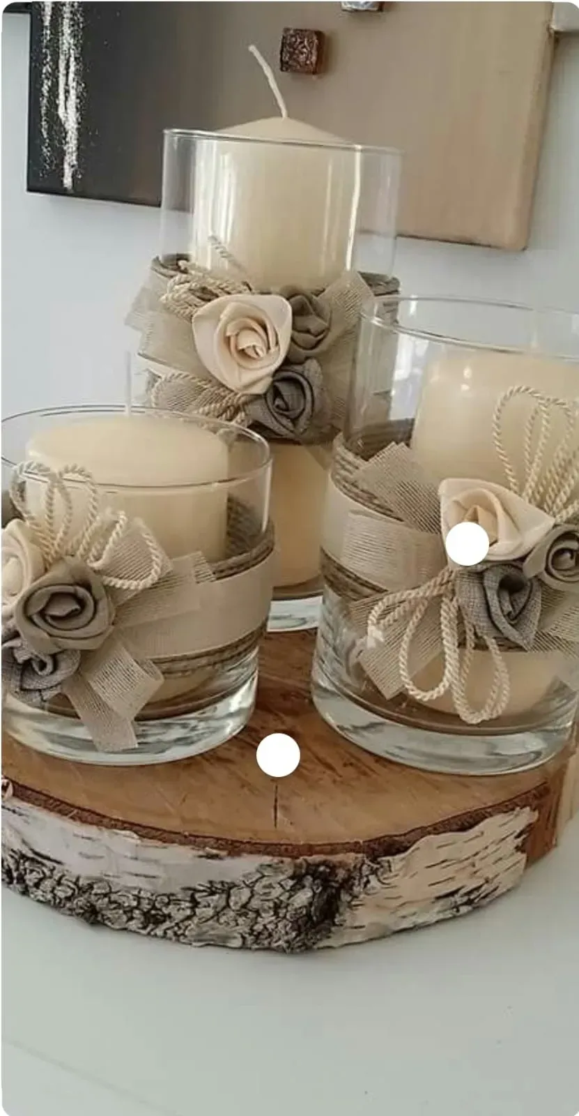 Tres velas color crema en portavelas de cristal sobre una bandeja de madera