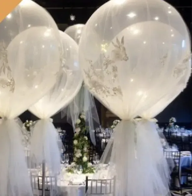 Globos blancos con cintas de tul decoran una mesa de evento tenuemente iluminada por la noche.
