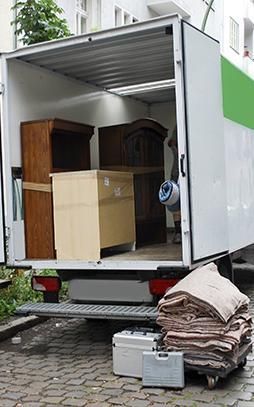 Un camión de mudanzas lleno de muebles está estacionado en una calle adoquinada.