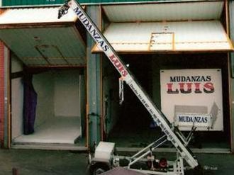 Un camión que dice mudanzas luis está estacionado frente a un edificio