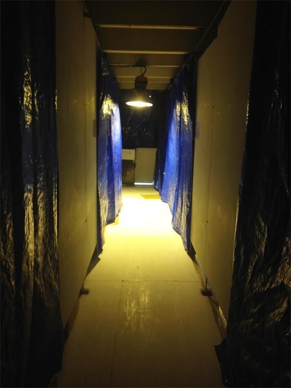 Un pasillo oscuro con lonas azules en las paredes.