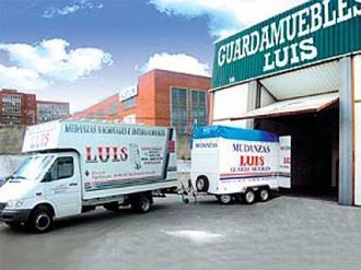 Una camioneta blanca con la palabra Luis en el costado está estacionada frente a un edificio.