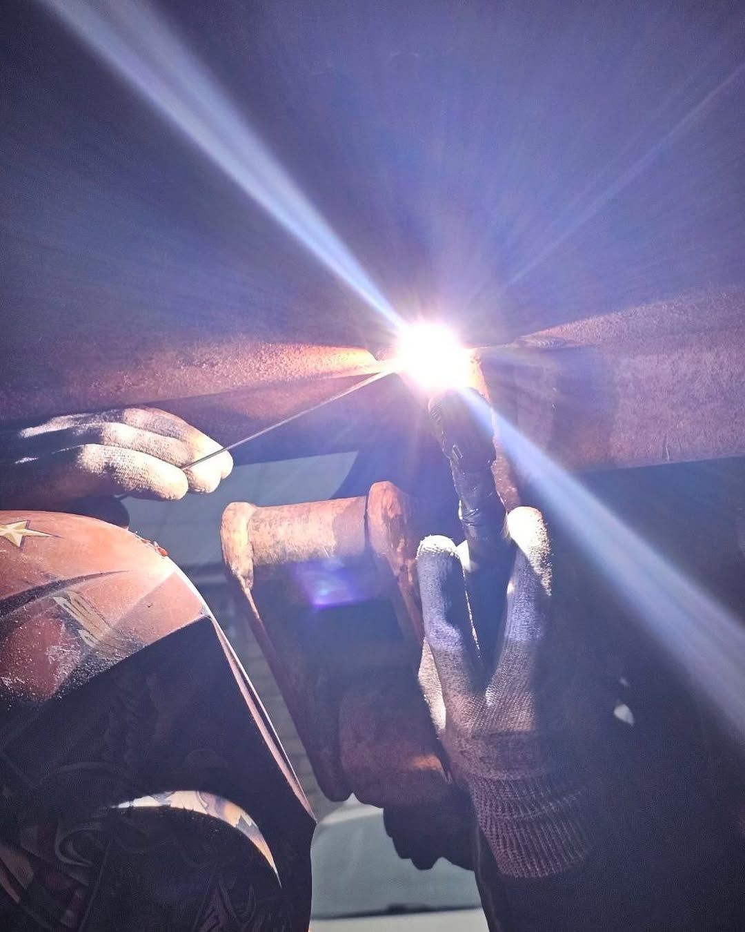 Soudeur en tenue de protection travaillant du métal. Une main tient l'électrode.