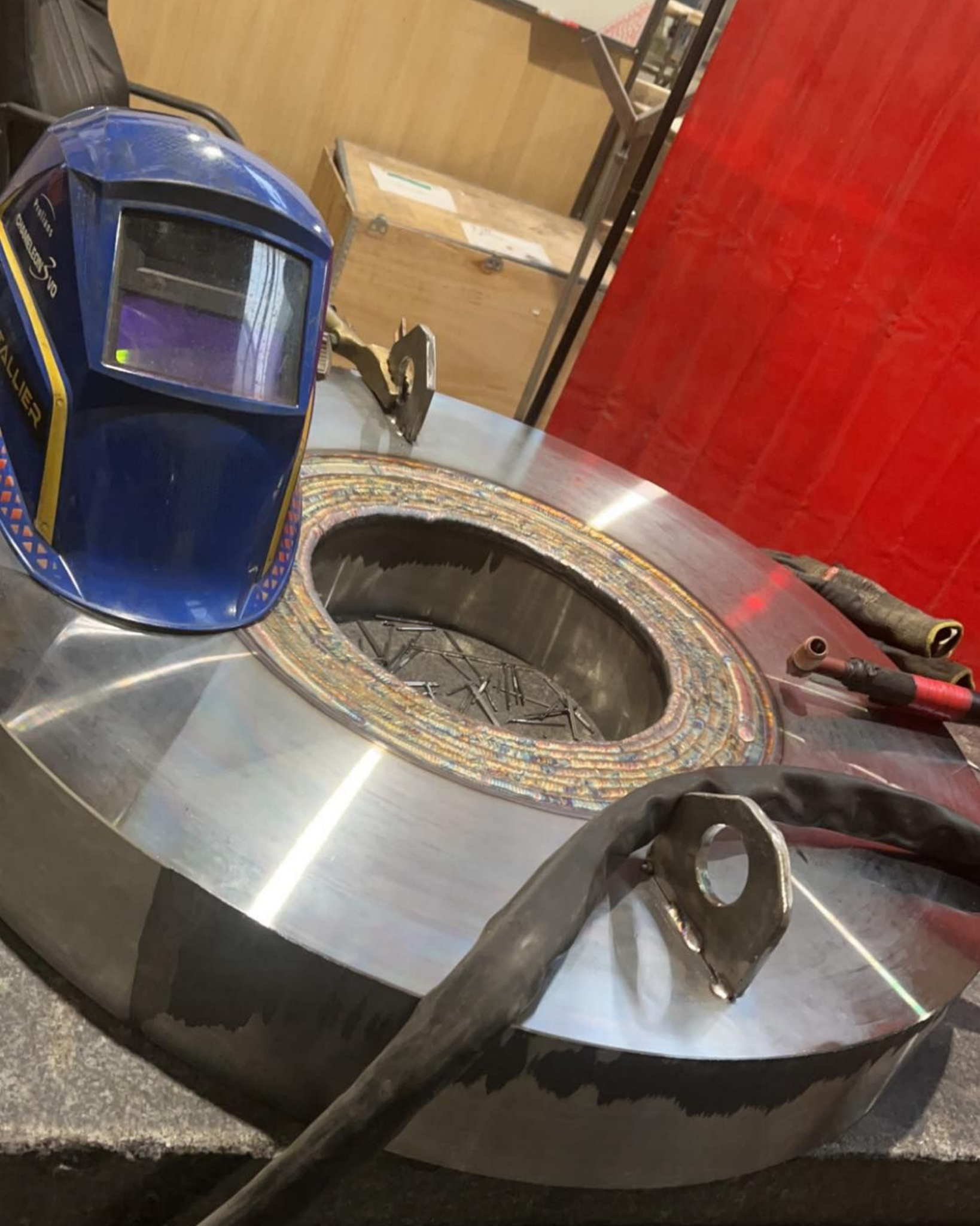 Un casque de soudeur posé sur un rouleau métallique.