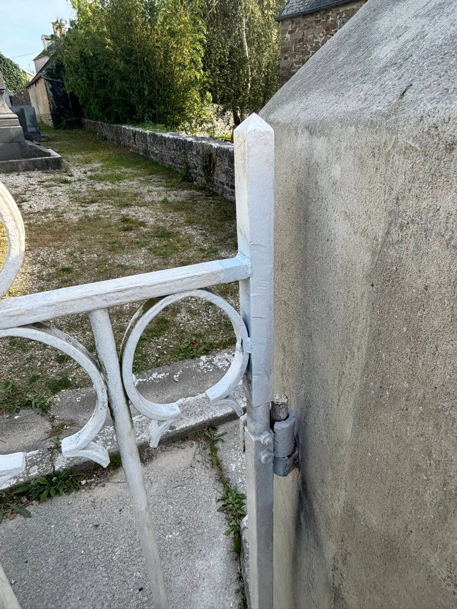 Portail en métal blanc fixé à un mur de pierre.