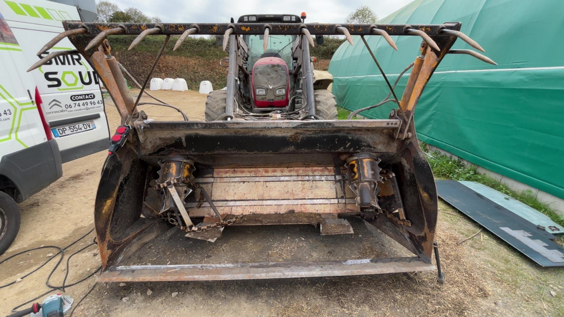 Une chargeuse équipée d'un grand godet et d'une pince.