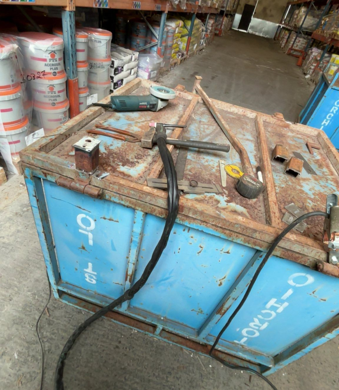 Benne à déchet avec des outils dessus, à l'intérieur d'un entrepôt.