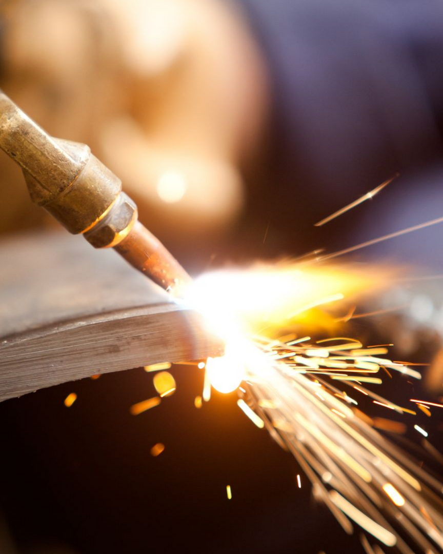 Un soudeur utilise une torche pour créer des étincelles et faire fondre le métal.
