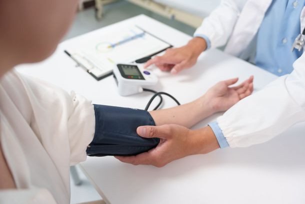 Un médecin prend la tension artérielle d'un patient à l'aide d'un tensiomètre électronique dans un cabinet médical.