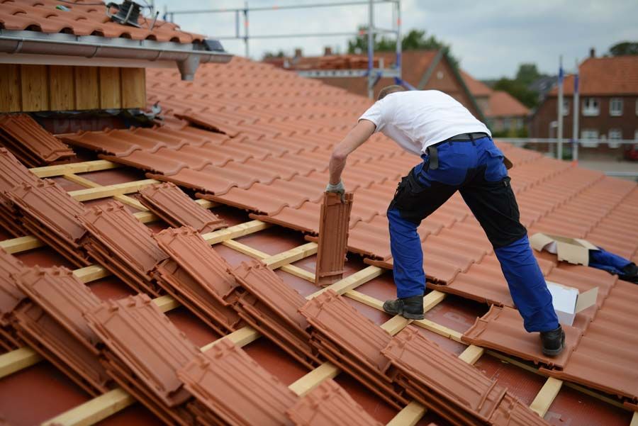 Artisan couvreur qui pose des tuiles