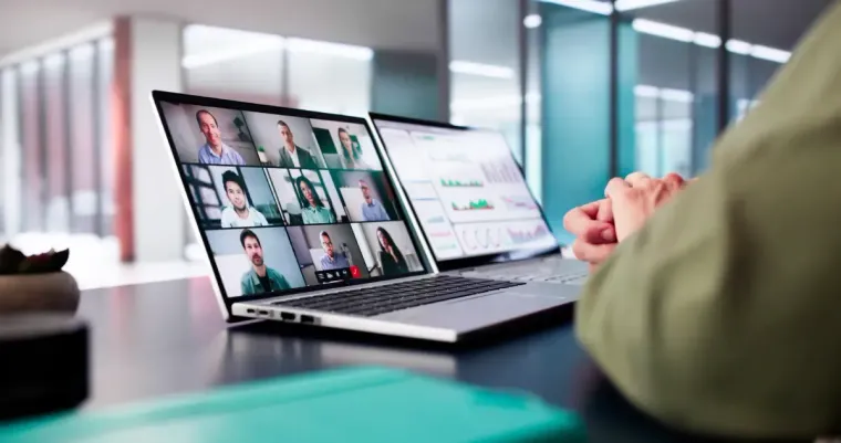 Una persona participa en una videollamada usando un portátil; otro portátil muestra gráficos.