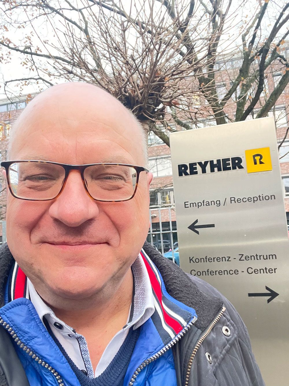 Lars Zimmermann steht vor dem Schild von der Zentrale von F.REYHER Nachf. GmbH & Co. KG