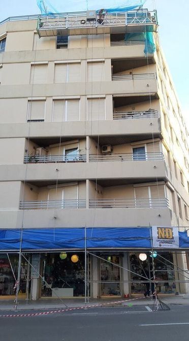 Un gran edificio con balcones y andamios a los lados.