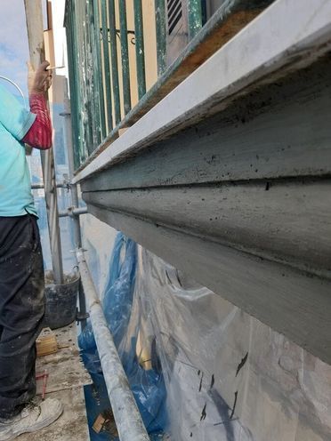 Un hombre está de pie en un andamio pintando una pared.
