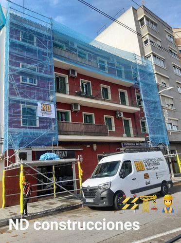 Una furgoneta blanca está estacionada delante de un edificio en construcción.