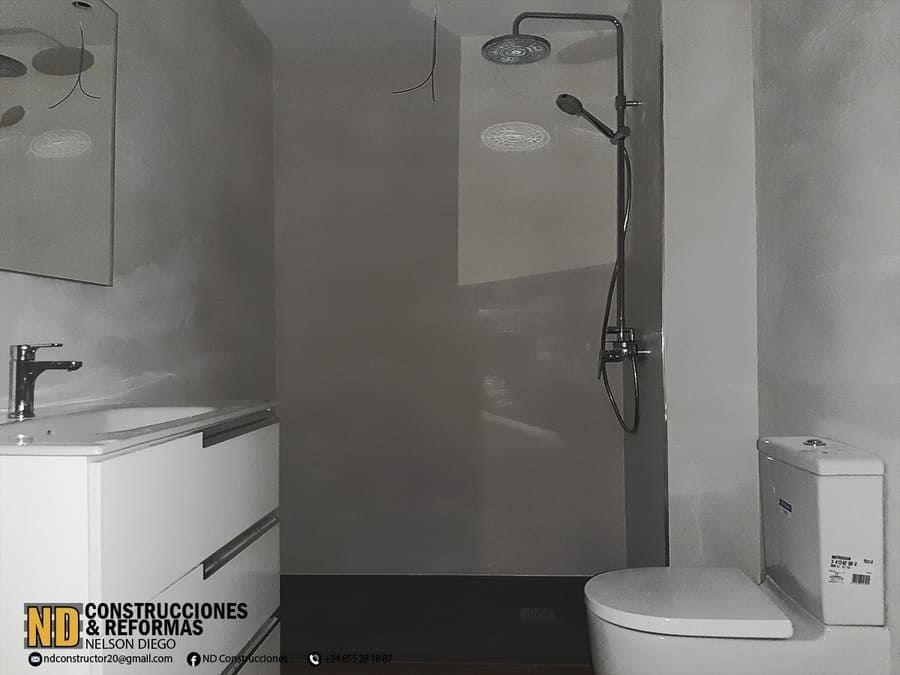 Un baño con inodoro, lavabo, espejo y ducha.