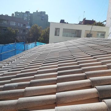 Un tejado con muchas tejas y un edificio al fondo.