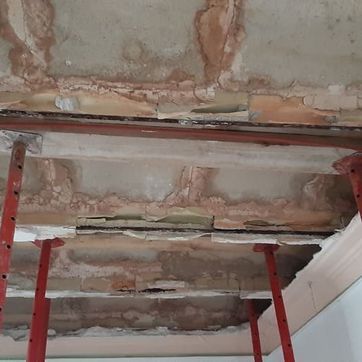 Un techo con un agujero y una escalera colgando de él.