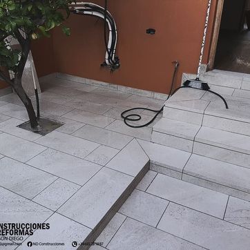 Un suelo de baldosas con escaleras y un árbol al fondo.